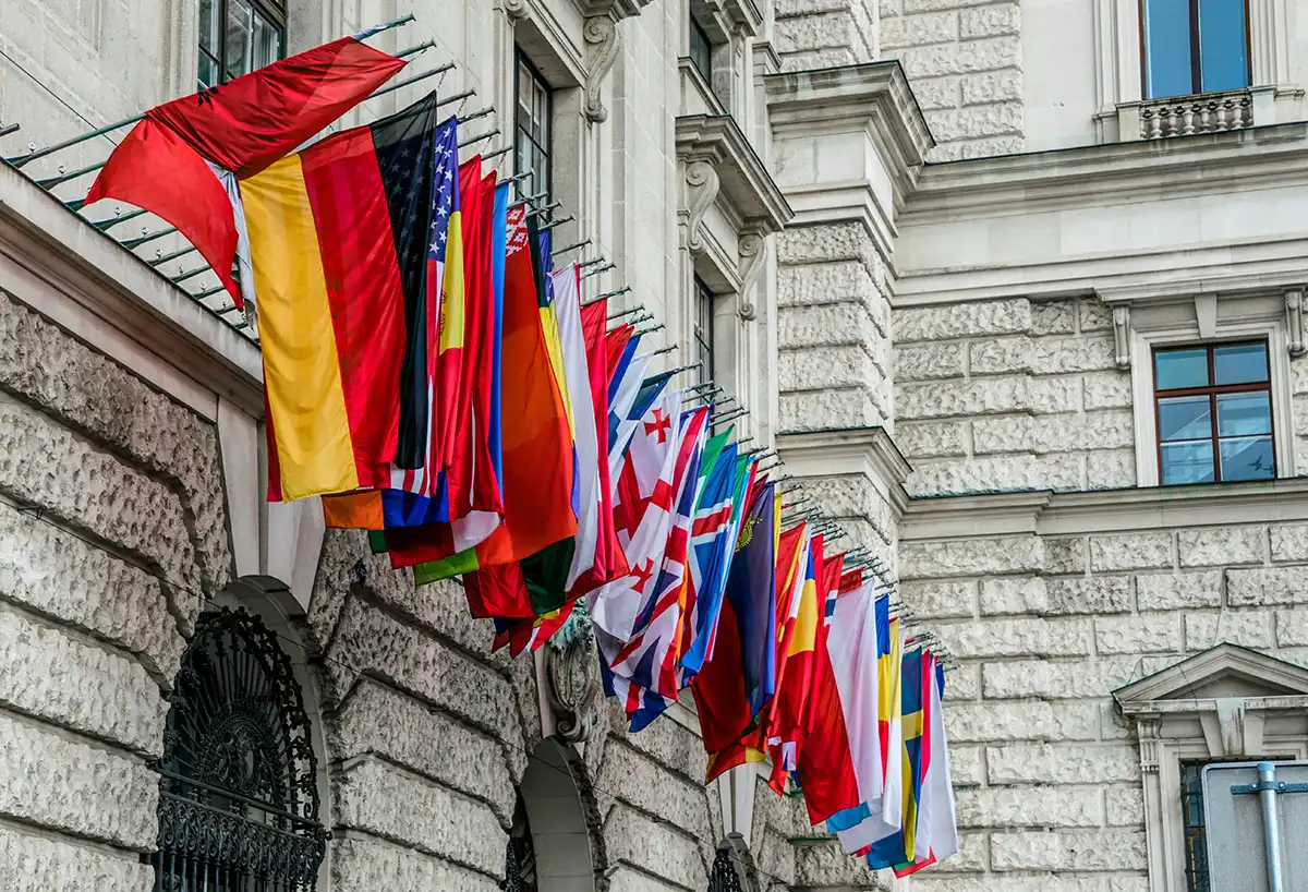 Rangée de drapeaux nationaux sur la façade d'un bâtiment diplomatique, symbole des représentations internationales qu'un ministère des Affaires étrangères entretient à travers le monde.
