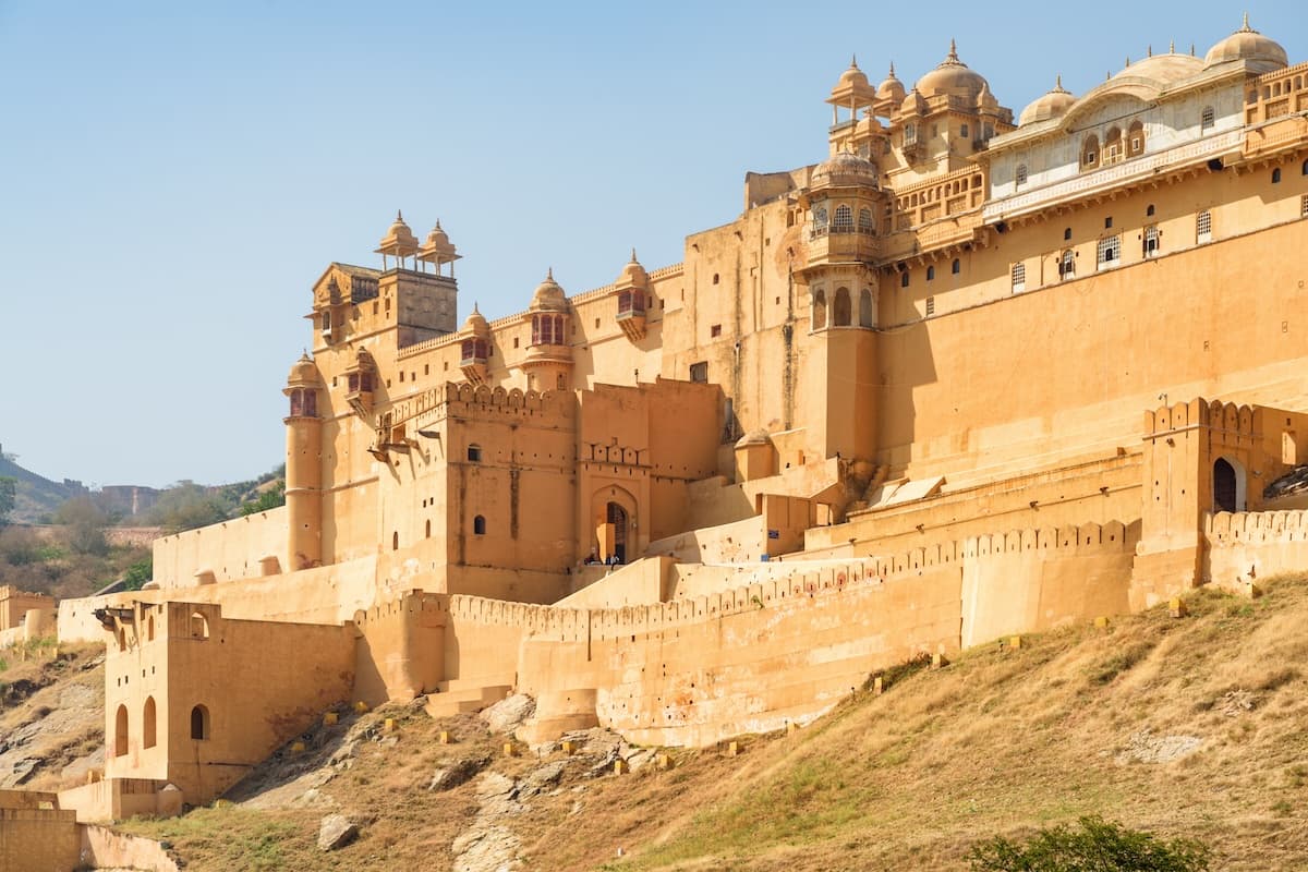 Le Fort d'Amber au-dessus du lac Maota près de Jaipur au Rajasthan — murs de grès, cours en terrasses et les contreforts de l'Aravalli.